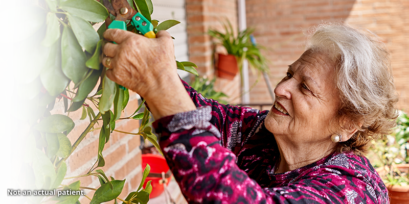 Older woman tending to a plant.