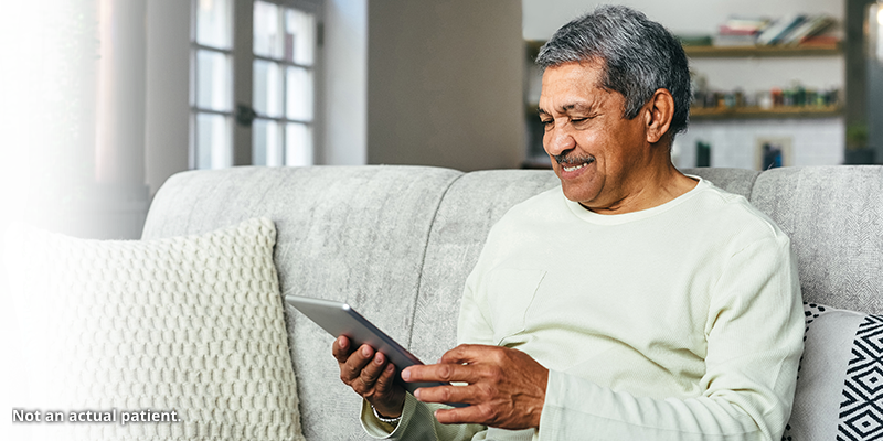 Man smiling at a tablet.