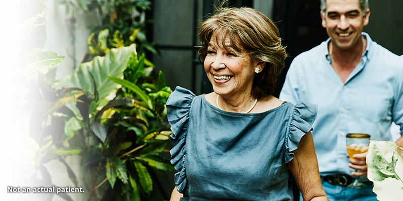 Older woman smiling with a plant.